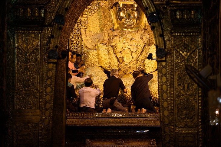 Applying gold leaf to the Mahamuni Buddha figure